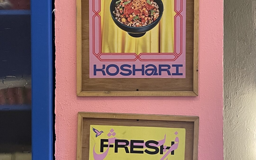A pink, blue, and yellow sign advertises "Koshari, Fresh out of Cairo"; Koshari is written in Arabic and English